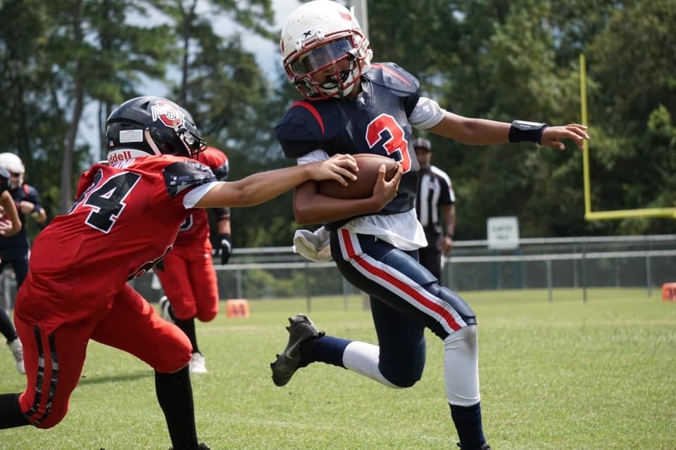 Kid playing football on a youth football team in Houston