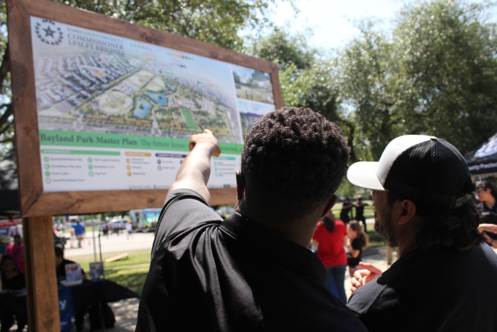 Precinct 4 project manager Archie Thompson describes the various changes coming to the park with one of the local little league baseball coaches whose team plays in Bayland Park. (Melissa Enaje/Community Impact)