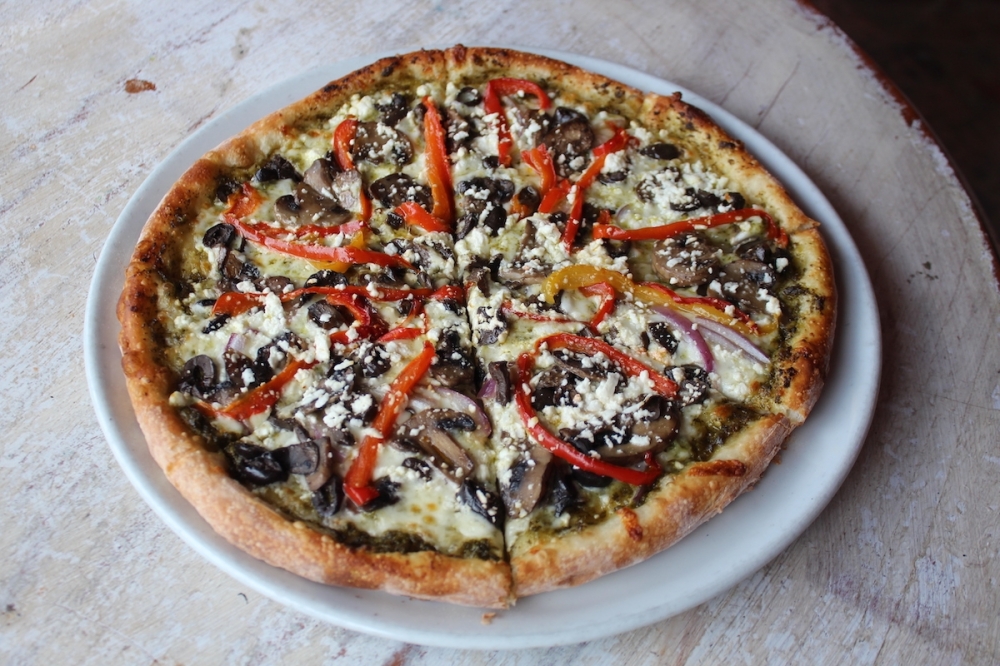 The vegetable pizza ($14) has bell peppers, onions, mushrooms, olives, feta cheese and pesto sauce. (Sarah Hernandez/Community Impact)
