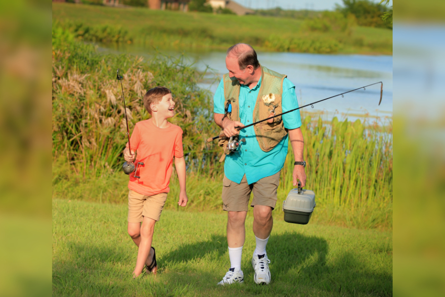 People by fishing pond in neighborhood with new construction homes in Buda