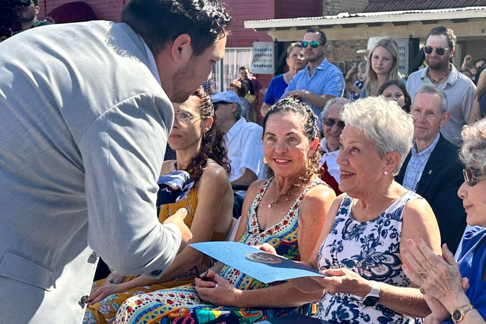 Christian Palacios, field representative for U.S Congressman Michael Cloud, presented Billy Waugh’s widow, Lynn Waugh, a U.S. flag and certificate. (Amanda Cutshall/Community Impact)