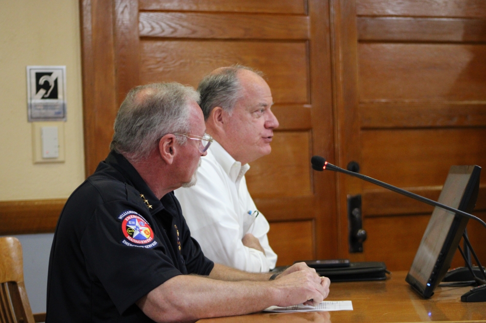 (From left) Williamson County Emergency Management Director Bruce Clements and Senior Director of Infrastructure Bob Daigh discuss FEMA programs and road updates county during a July 11 county commissioners meeting. (Anna Maness/Community Impact)