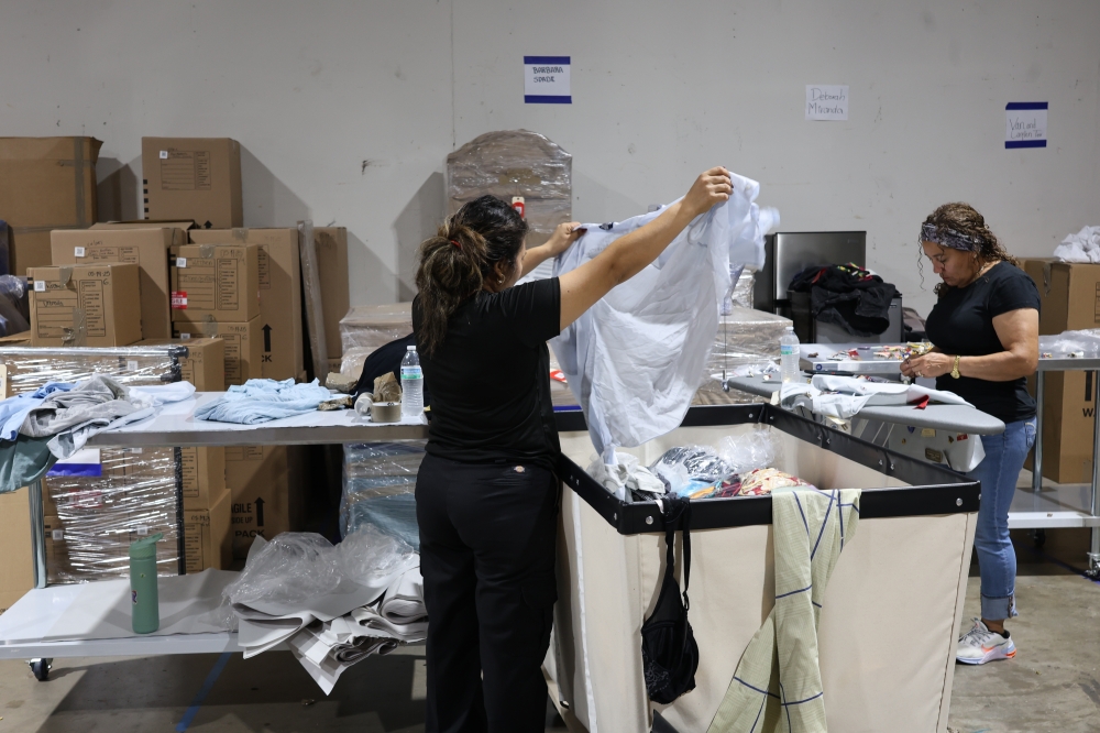 Woman folding clothes to repair fire damage in Houston