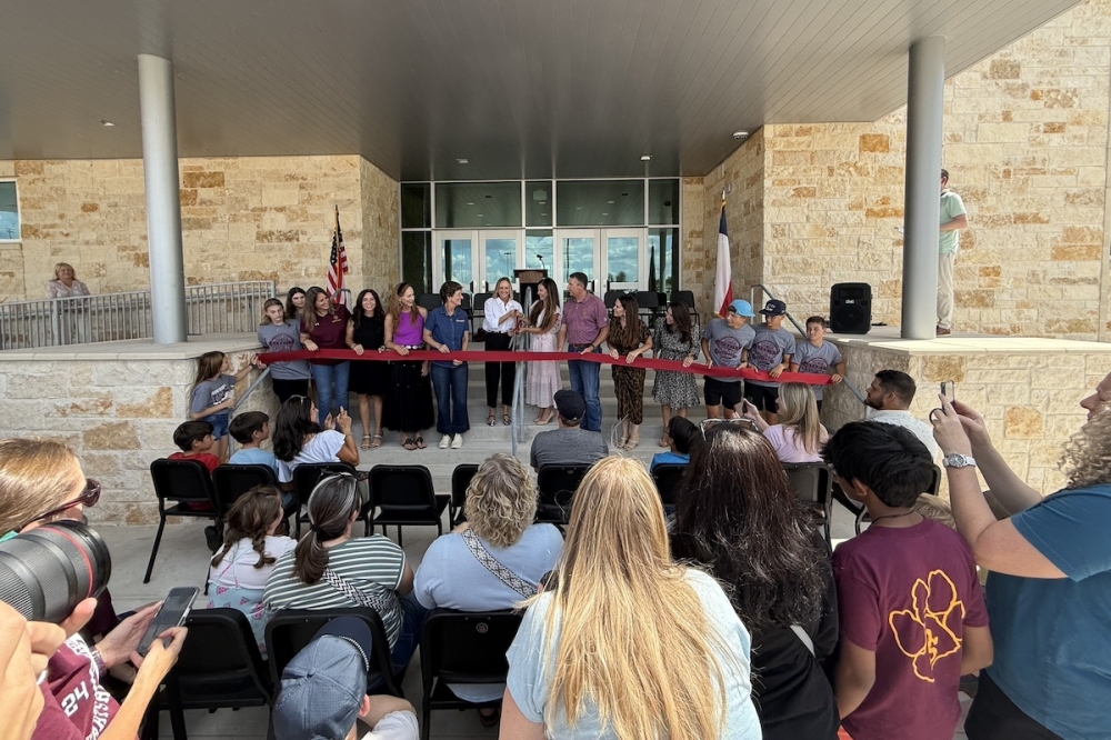 Dripping Springs ISD board members (center), staff and community members marked the opening of the expanded Sycamore Springs Middle School campus with a ribbon cutting ceremony Aug. 6. (Elisabeth Jimenez/Community Impact)