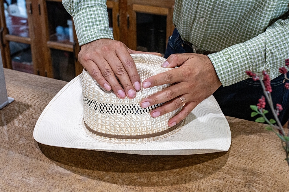 Emilio Rangel gives the crown of a hat a cattleman crease. The shape is characterized by a taller, narrower crown with a center crease and two side indentations. (Joel Valley/Community Impact)