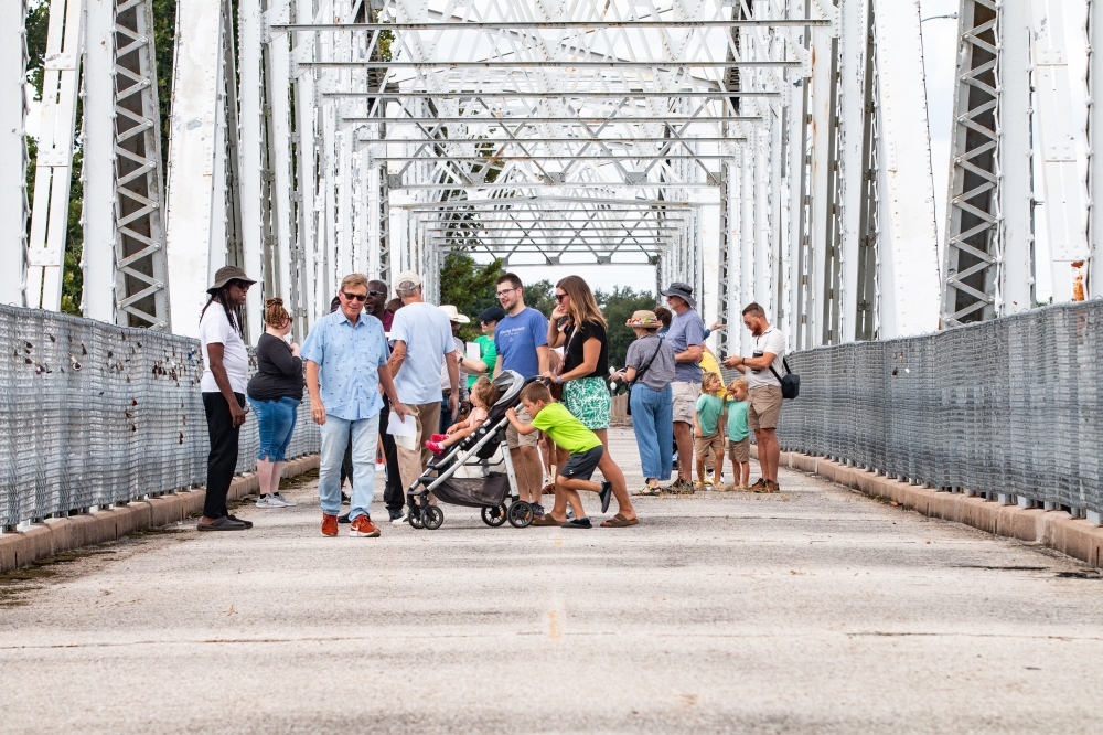 Bastrop residents walk across the Old Iron Bridge following a rehabilitation kickoff event July 26. (Joel Valley/Community Impact)