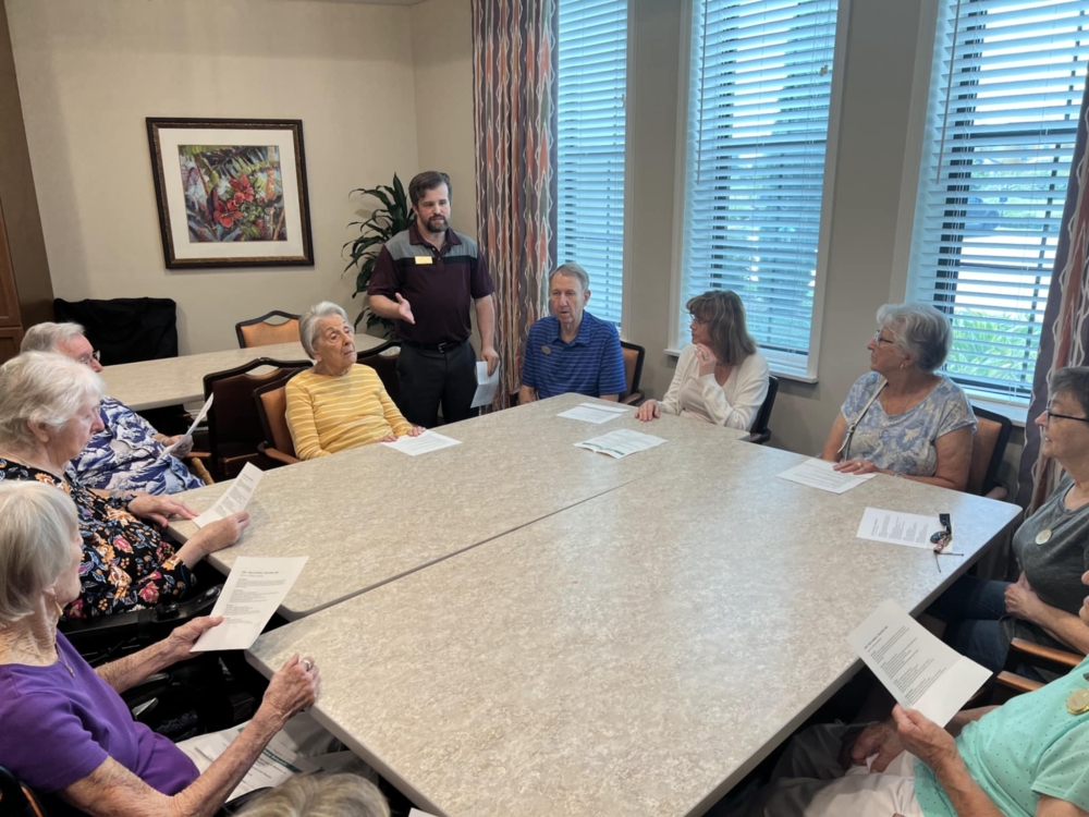 Senior living residents sitting around a table reading scripts