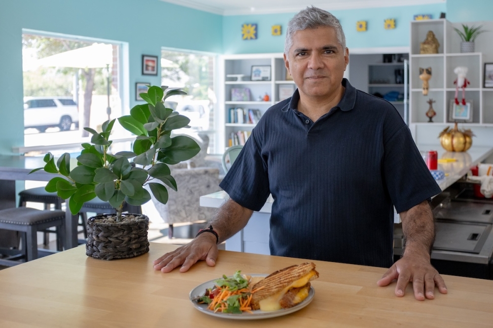 U.K. restaurateur, Menesh Agnihotri, stands as new owner of Naturally Cafe in Gruene Lakes Village, New Braunfels. (Ethan Thomas/Community Impact)