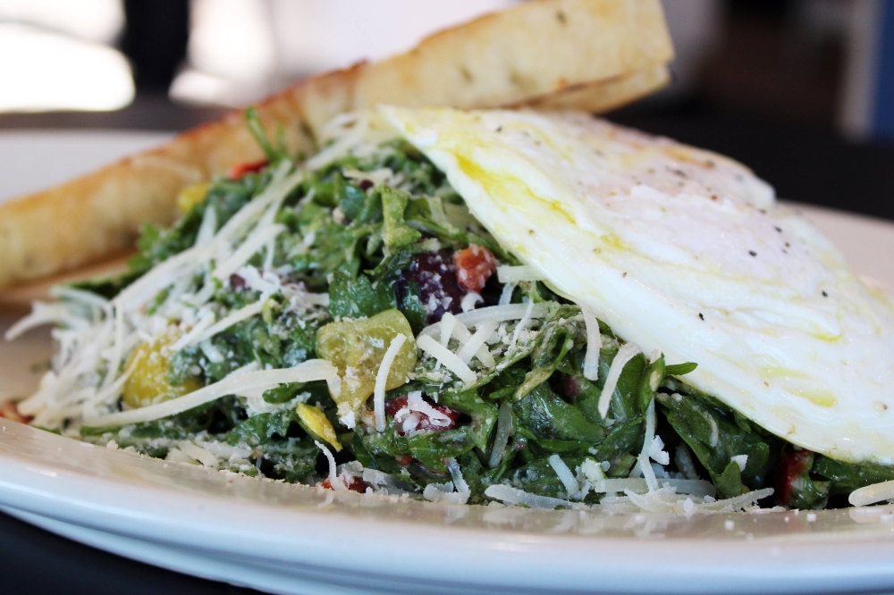 Italian breakfast salad ($11.95) features two over-medium eggs, arugula, roasted red peppers, Kalamata olives, pepperoncini, soppressata, provolone, parmesan cheese and toasted focaccia bread. (Karen Chaney/Community Impact)
