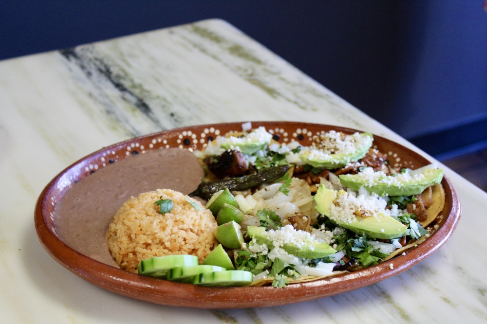 The street taco plate ($14.99) is a customer favorite and includes five tacos served on corn tortilla, topped with a choice of protein, avocado, queso fresco, grilled onions and cilantro and is served with cucumber, limes, salsa, rice and beans. (Jovanna Aguilar/Community Impact)