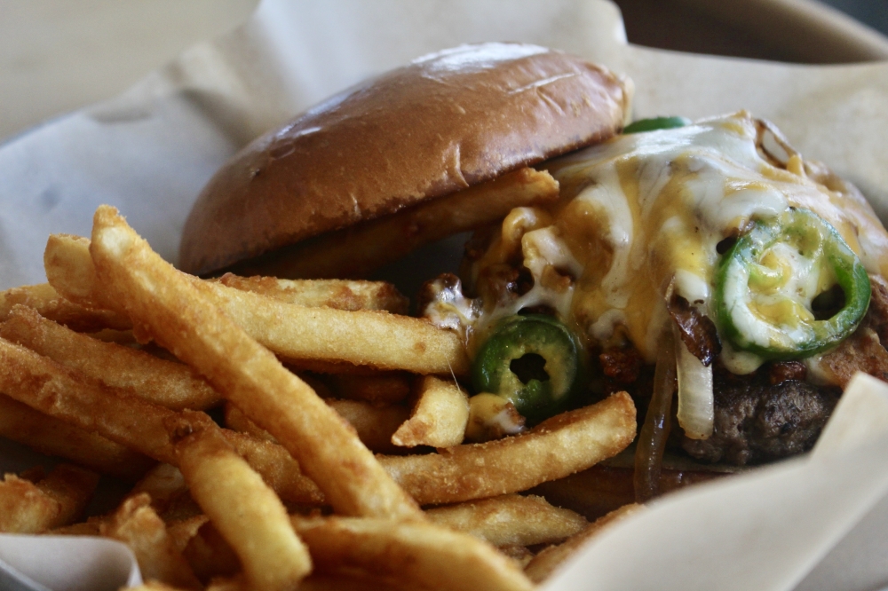 The Frito Bandito Burger ($10.50) is a beef patty with house-made Lone Star chili, corn chips, grilled onions, fresh jalapenos and melted cheese. (Katlynn Fox/Community Impact)